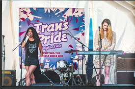 Powderpaint perform on stage in front of a Trans Pride banner. Photo credit: Lollo Popper